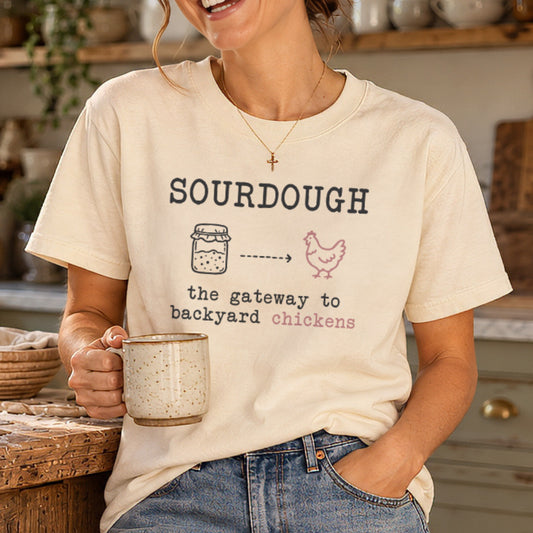 Woman in a cottage kitchen wearing an ivory sourdough gateway to backyard chickens t-shirt